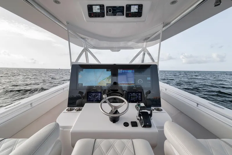  Yacht Photos Pics 2024 Contender 44 ST boat helm with advanced navigation screens on open sea.