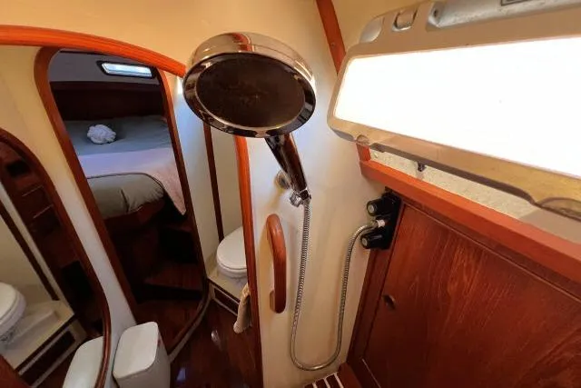 Unicorn Yacht Photos Pics 1988 Hylas Custom 44 yacht bathroom with shower, wooden accents, and cozy cabin view.