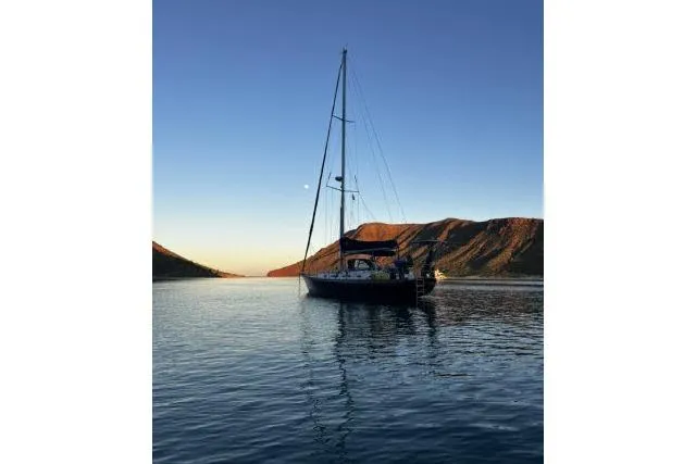 Unicorn Yacht Photos Pics Sailboat Hylas Custom 44 (1988) on serene water at sunset with mountains.