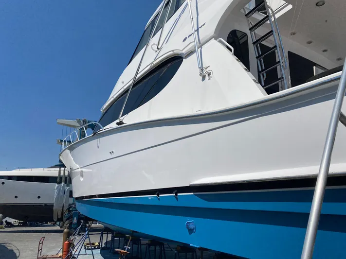 Temptation Yacht Photos Pics 2008 Hatteras 77 Convertible yacht with blue hull, docked under clear sky.