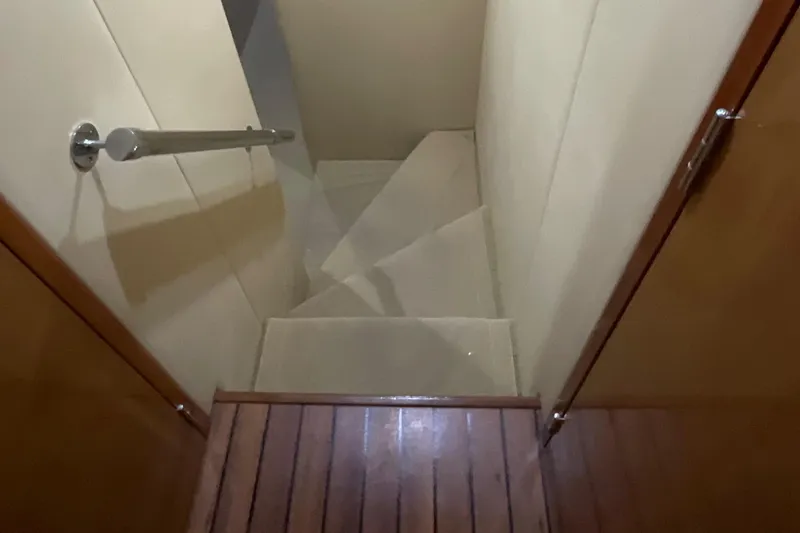 Temptation Yacht Photos Pics Staircase inside 2008 Hatteras 77 Convertible yacht, featuring wooden steps and sleek design.