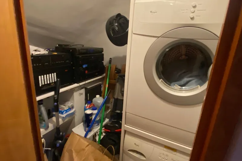 Temptation Yacht Photos Pics Laundry room with stacked washer-dryer and storage shelves on a 2008 Hatteras 77 Convertible yacht.