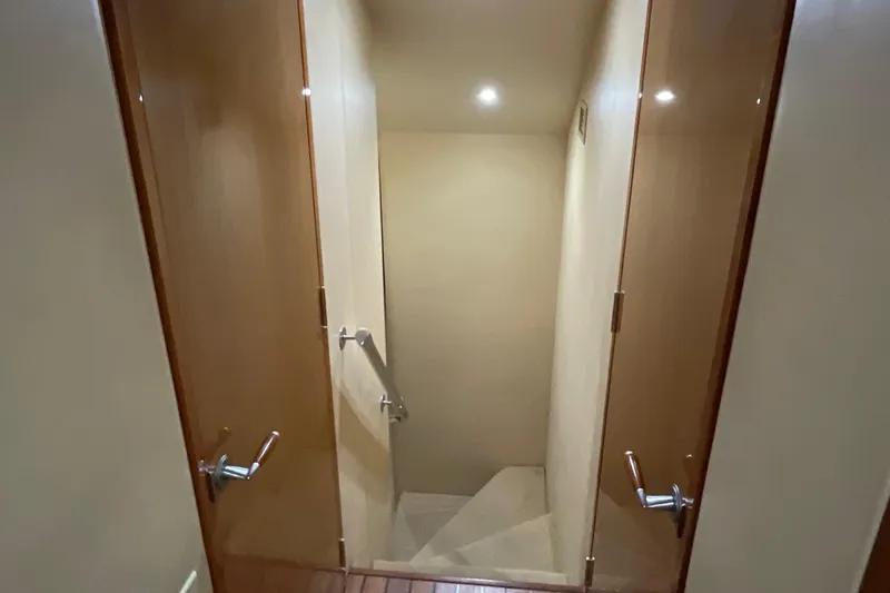 Temptation Yacht Photos Pics Staircase inside 2008 Hatteras 77 Convertible yacht with wooden doors and handrail.