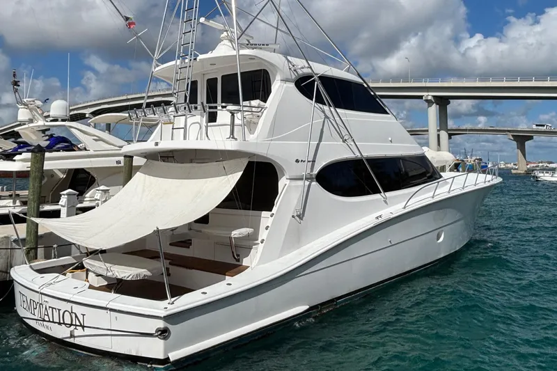 Temptation Yacht Photos Pics 2008 Hatteras 77 Convertible yacht docked in marina, under a blue sky.