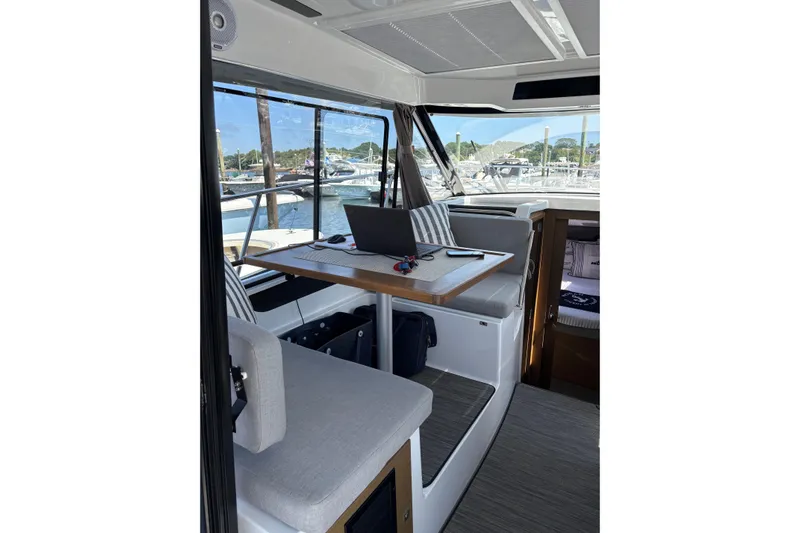  Yacht Photos Pics Interior of 2020 Jeanneau NC 895 boat with table, laptop, and marina view.