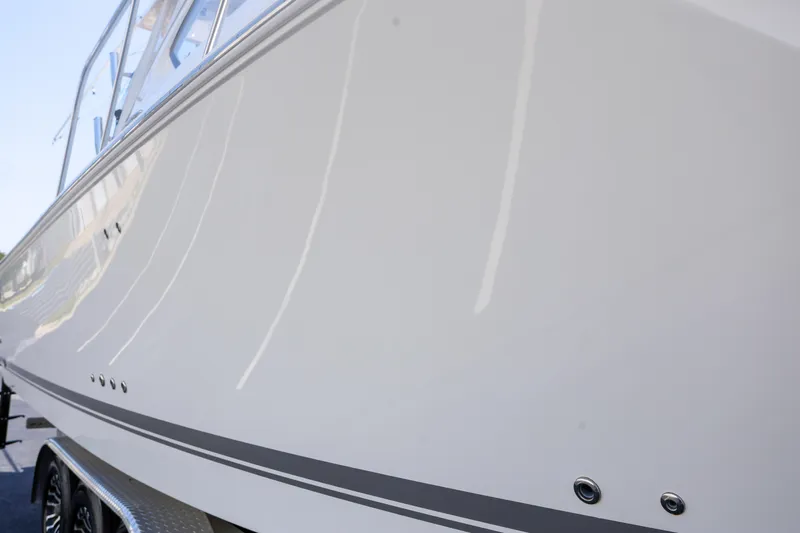  Yacht Photos Pics 2021 Pursuit OS 325 Offshore boat, sleek white hull, close-up view.