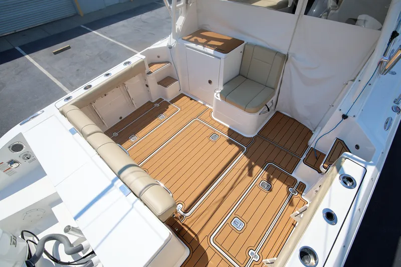  Yacht Photos Pics 2021 Pursuit OS 325 Offshore boat interior with teak flooring and cushioned seating.