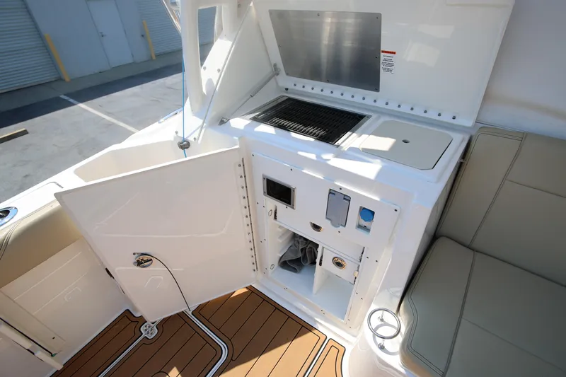  Yacht Photos Pics 2021 Pursuit OS 325 Offshore boat interior with open storage, grill, and seating area.