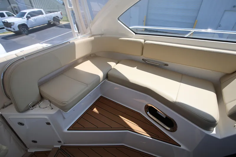  Yacht Photos Pics 2021 Pursuit OS 325 Offshore boat interior with beige seating and wood flooring.