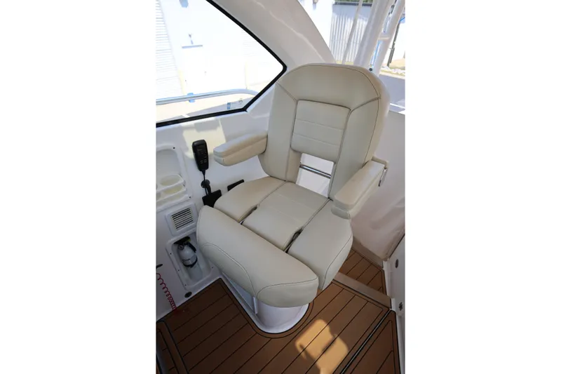  Yacht Photos Pics Captain's chair on 2021 Pursuit OS 325 Offshore boat, featuring beige upholstery and armrests.