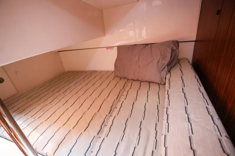  Yacht Photos Pics 2021 Pursuit OS 325 Offshore cabin bed with striped bedding and pillow.