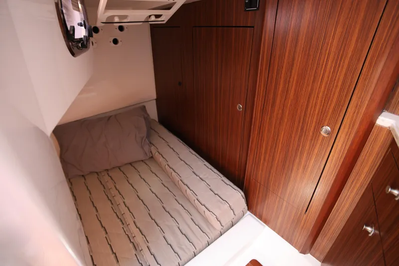  Yacht Photos Pics 2021 Pursuit OS 325 Offshore cabin interior with wood paneling and cozy bed.