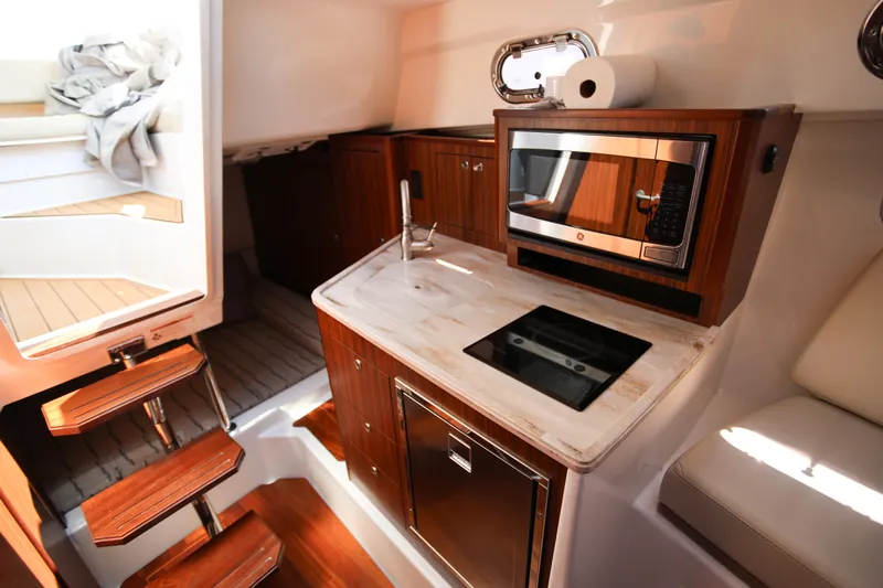  Yacht Photos Pics 2021 Pursuit OS 325 Offshore boat interior with kitchenette, featuring microwave and sink.