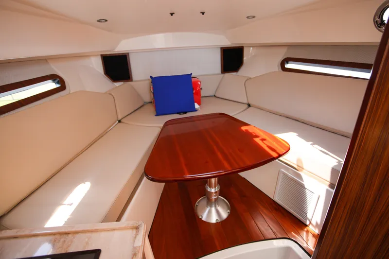  Yacht Photos Pics 2021 Pursuit OS 325 Offshore cabin with wooden table and beige seating.