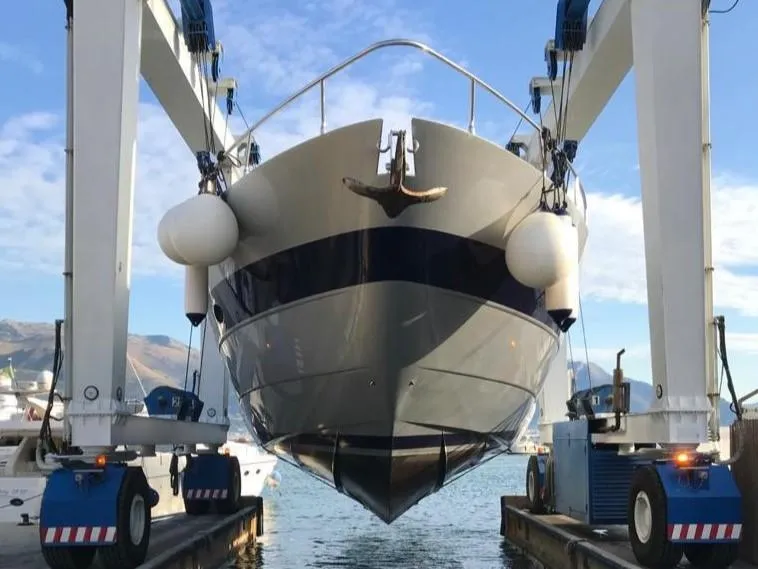 Pershing 76 yacht from 2005 being lifted in a marina setting.