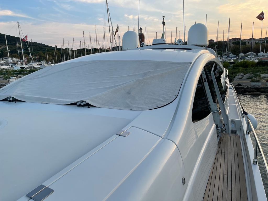 2005 Pershing 76 yacht docked, covered windshield, marina background at sunset.