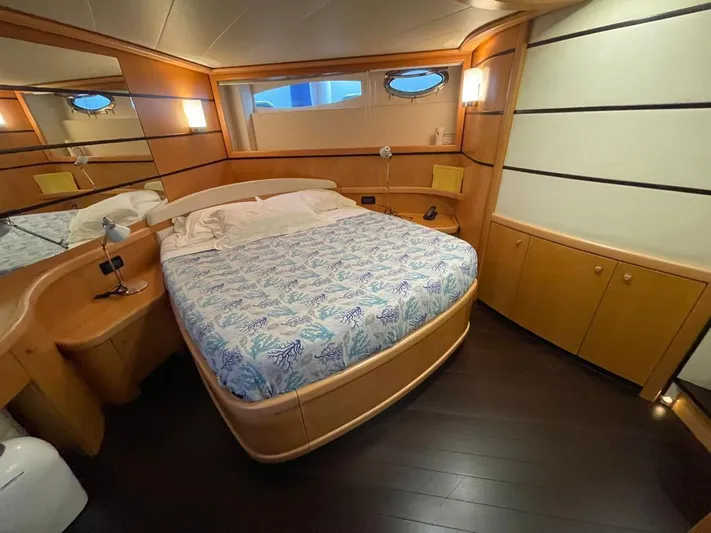  Yacht Photos Pics Luxurious bedroom interior on a 2005 Pershing 76 yacht, featuring elegant wood finishes.