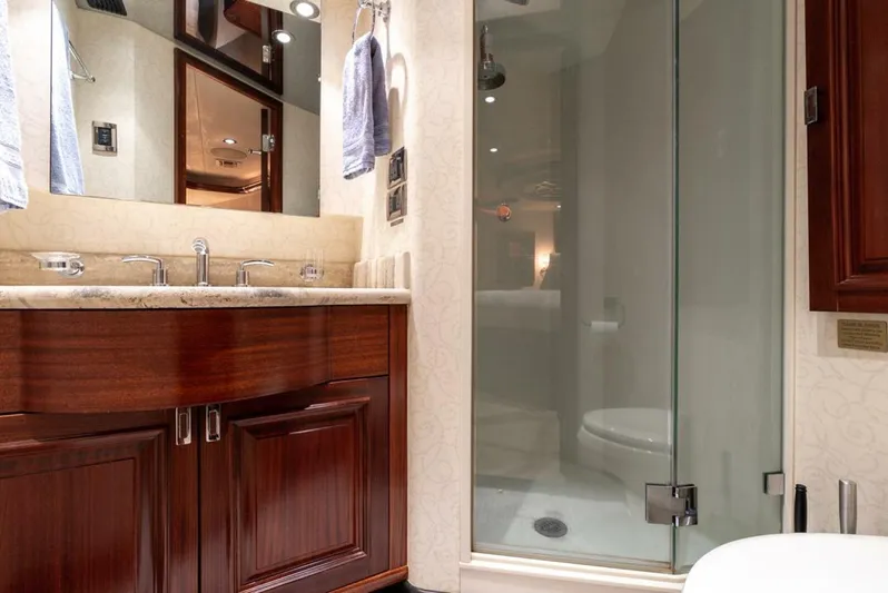Simplicity Yacht Photos Pics Luxurious bathroom in a 2012 Westport 112 yacht, featuring elegant wood cabinetry and glass shower.