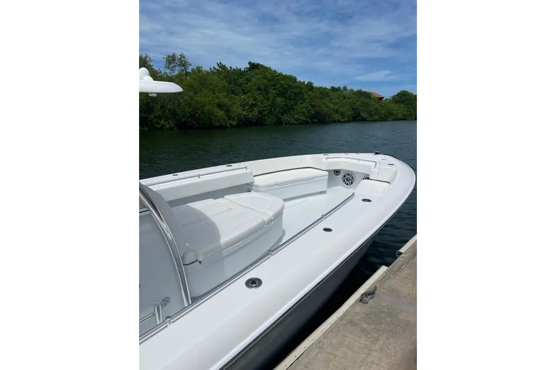  Yacht Photos Pics 2025 Contender 44 ST boat docked by lush greenery under a clear blue sky.