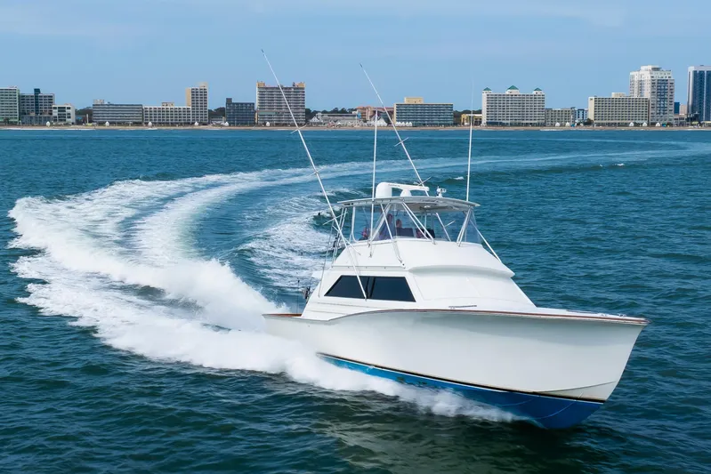 Spiros Yacht Photos Pics 1972 Jim Smith Custom Convertible boat cruising on ocean near city skyline.