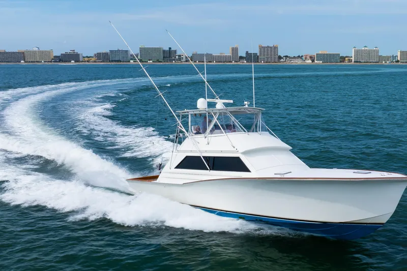 Spiros Yacht Photos Pics 1972 Jim Smith Custom Convertible boat cruising on ocean near city skyline.