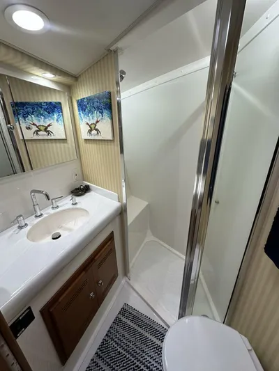Off Season Yacht Photos Pics Luxurious bathroom in 2006 Cabo 48 Convertible yacht with shower, sink, and artwork.