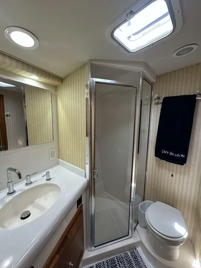 Off Season Yacht Photos Pics Luxurious bathroom in 2006 Cabo 48 Convertible yacht with shower, sink, and toilet.