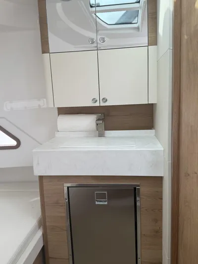  Yacht Photos Pics 2023 Bertram 39 CC interior with modern sink, cabinets, and stainless steel fridge.
