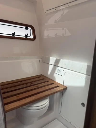  Yacht Photos Pics 2023 Bertram 39 CC boat bathroom with wooden seat and window.