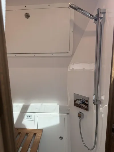  Yacht Photos Pics 2023 Bertram 39 CC boat shower area with modern fixtures and wooden bench.