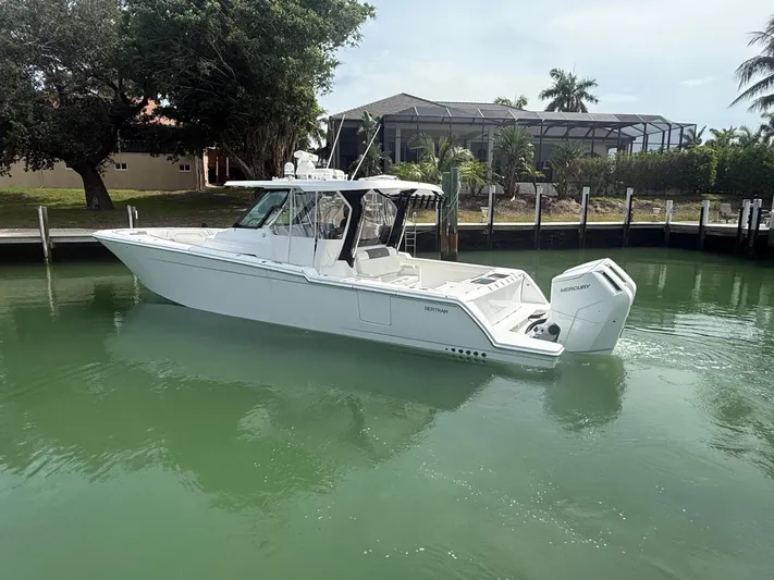  Yacht Photos Pics 2023 Bertram 39 CC boat in calm waters near a dock, surrounded by greenery.
