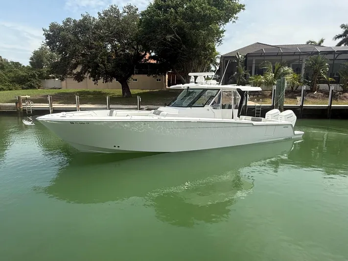  Yacht Photos Pics 2023 Bertram 39 CC boat docked in calm waters, surrounded by lush greenery.