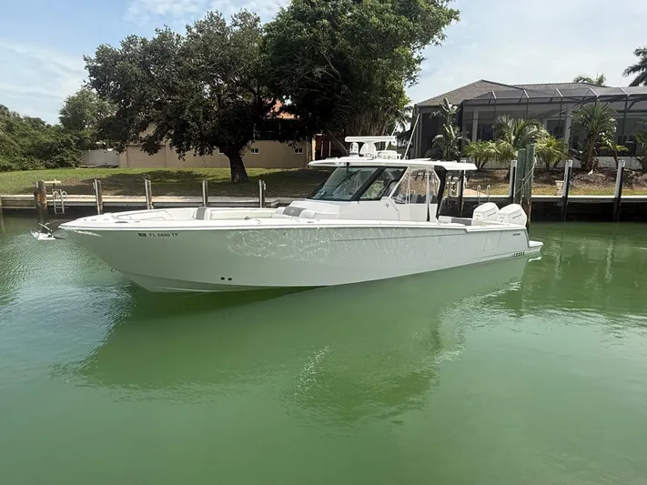  Yacht Photos Pics 2023 Bertram 39 CC boat docked on calm green water, surrounded by trees and houses.