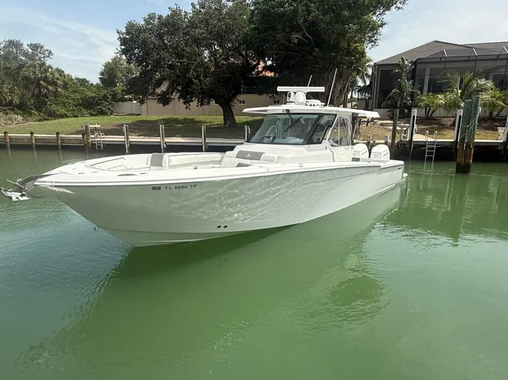  Yacht Photos Pics 2023 Bertram 39 CC boat docked in calm waters, surrounded by lush greenery.