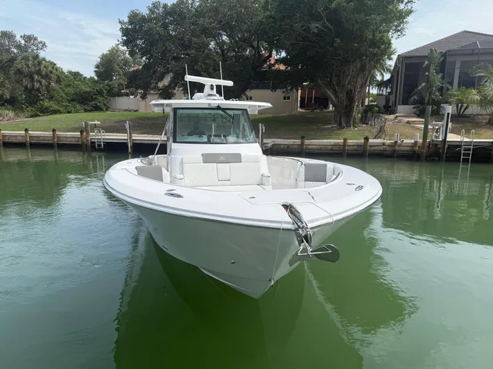  Yacht Photos Pics 2023 Bertram 39 CC boat docked in calm waters, surrounded by lush greenery.