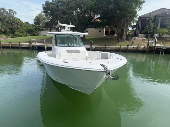  Yacht Photos Pics 2023 Bertram 39 CC boat docked in calm waters, surrounded by lush greenery.