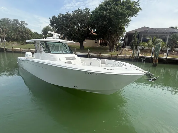  Yacht Photos Pics 2023 Bertram 39 CC boat docked in calm waters, surrounded by lush greenery.