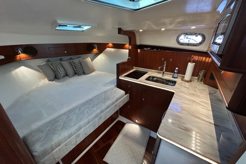  Yacht Photos Pics Luxurious interior of 2023 Pursuit OS 385 Offshore yacht with bed and kitchenette.