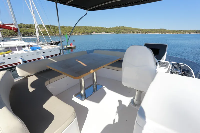  Yacht Photos Pics Flybridge of 2019 Azimut Magellano 53 yacht with seating and table, overlooking serene waters.