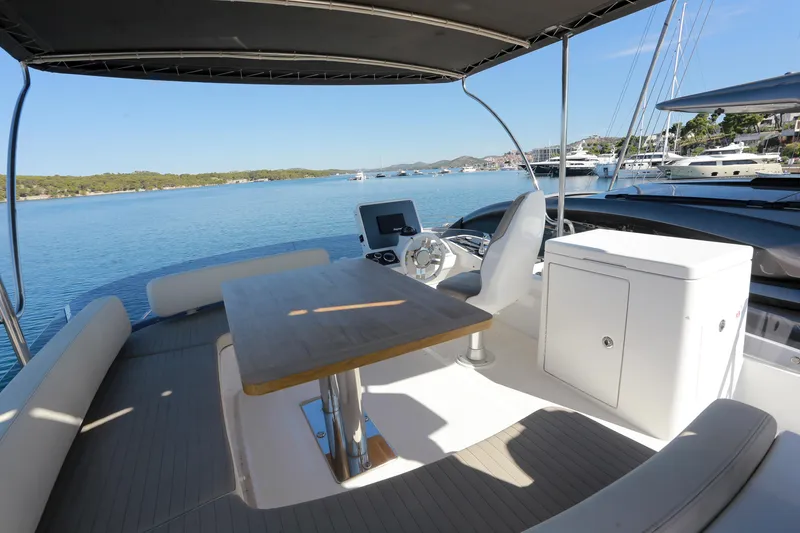  Yacht Photos Pics Flybridge of 2019 Azimut Magellano 53 yacht with seating and table, overlooking serene waters.