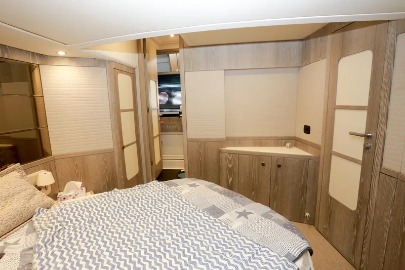  Yacht Photos Pics Luxurious bedroom interior of 2019 Azimut Magellano 53 yacht, featuring modern wood finishes.