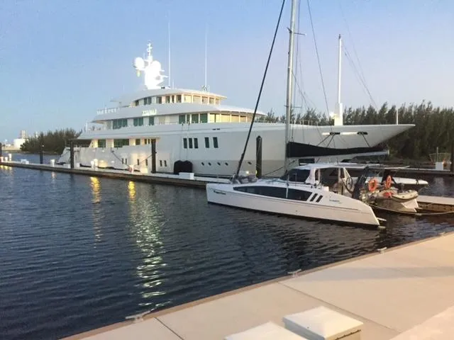 Pepper Love Yacht Photos Pics 2020 Seawind 1190 Sport catamaran docked beside a large yacht at sunset.