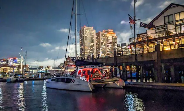 Pepper Love Yacht Photos Pics 2020 Seawind 1190 Sport catamaran docked at a vibrant city marina at night.