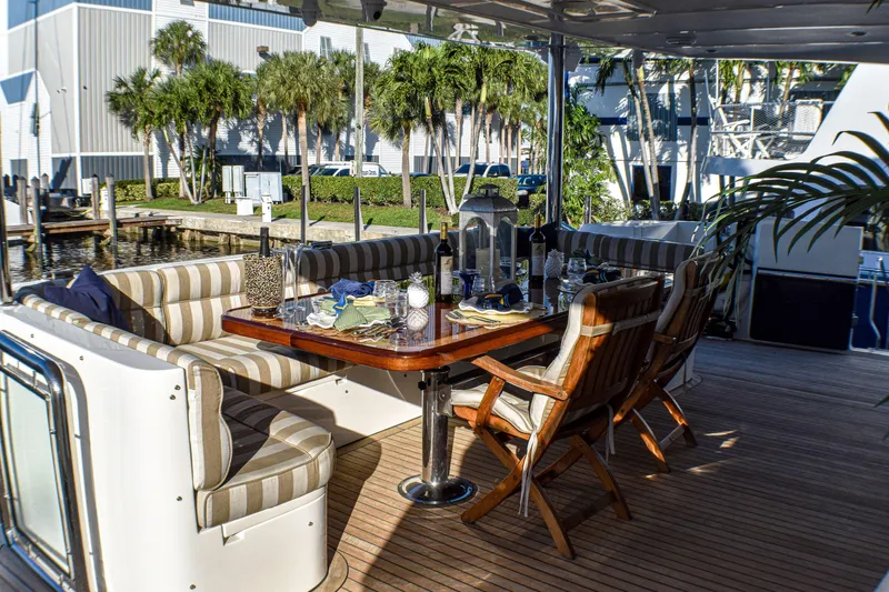 Magic Moments Yacht Photos Pics Outdoor dining area on 2006 Johnson Country Kitchen yacht, featuring striped seating and wooden table.