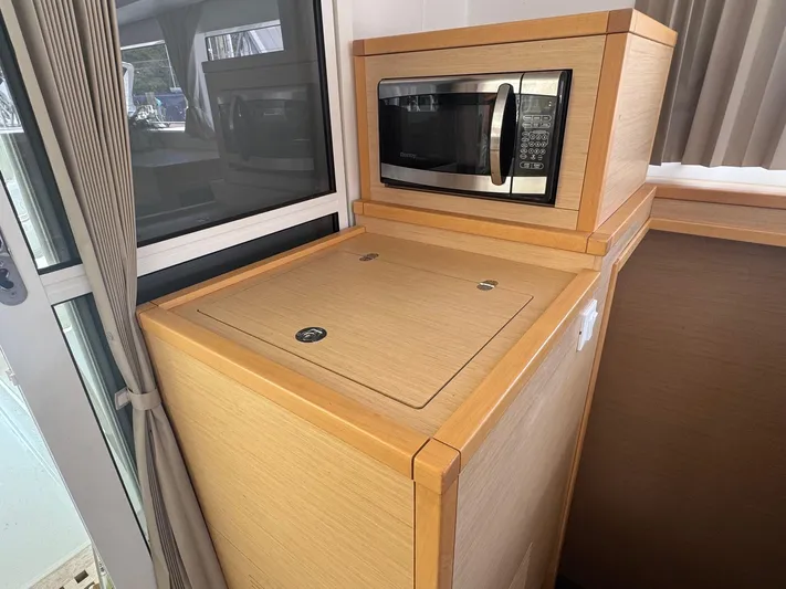 Serenity Yacht Photos Pics Microwave in 2016 Lagoon 400 S2 yacht kitchen, featuring wooden cabinetry and window view.
