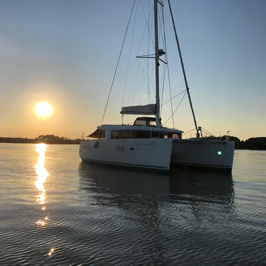 Serenity Yacht Photos Pics 2016 Lagoon 400 S2 catamaran at sunset on calm water.
