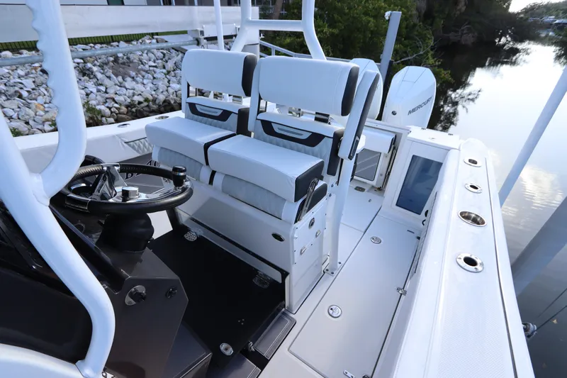  Yacht Photos Pics 2023 Blackfin 272 CC boat interior with dual seating and steering wheel, docked by a calm river.