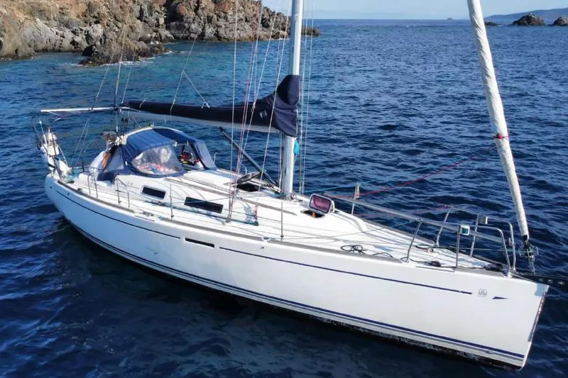  Yacht Photos Pics 2006 Dufour 34 Performance sailboat anchored in clear blue waters near rocky coastline.