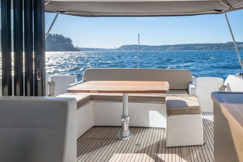 Bee's Knees Yacht Photos Pics 2017 Jeanneau NC 14 yacht interior with seating and table, overlooking scenic ocean view.