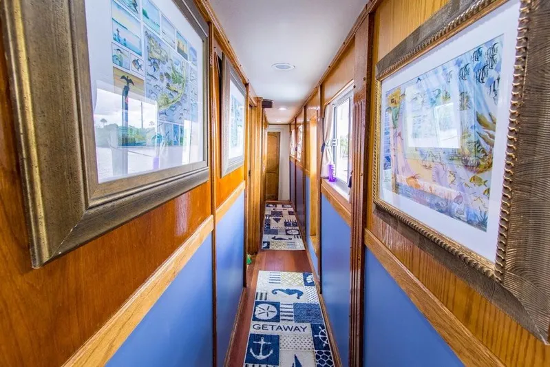 Timeless Yacht Photos Pics Narrow hallway on 1983 Benetti Custom Lloyds M.Y. yacht with framed artwork and nautical-themed carpet.